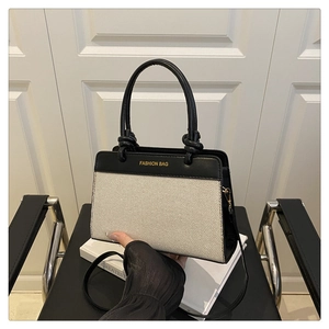 Detail of the stitching on the black leather and beige canvas tote with fashion lettering