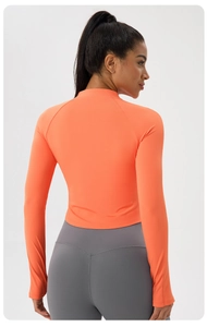 Back view of slim fit orange long sleeve sports top and high waist grey yoga pants