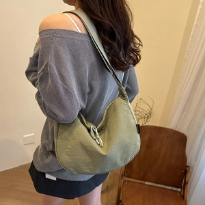 Minimalist green nylon crescent bag with adjustable strap and knot detail