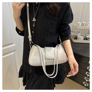 Close-up of silver pearlescent leather shoulder bag with buckle and brand logo