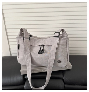 Detail of light gray nylon bag showing waterproof texture and zipper compartments