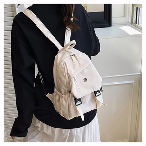Détail d'un mini sac à dos en nylon crème avec boucle réglable et poches latérales
