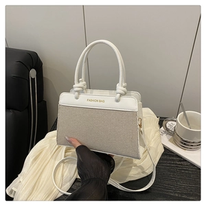 Detail view of woven tote bag with white leather trim and gold fashion bag lettering