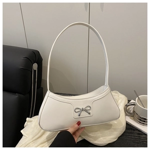 Detailed view of white croissant bag with silver bow accent and minimalist shoulder strap