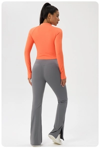 Detail view of orange slim-fit zip-up yoga top and grey flared leggings with side slits