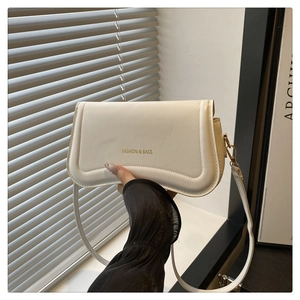 Close-up of cream white PU leather shoulder bag with golden metal hardware and flap closure