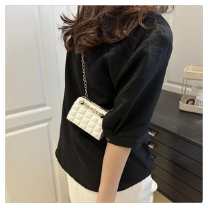 Close-up of a white quilted crossbody bag with golden chain strap on a model