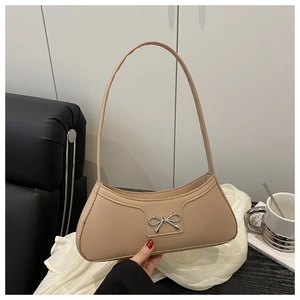 Detail view of an apricot baguette bag featuring a silver metal bow and slim shoulder strap