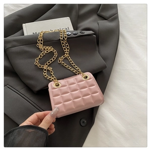 Detail of pink quilted crossbody bag with gold chain strap on black blazer background
