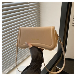 Close-up of beige leather shoulder bag with Fashion & Bags text and gold metal hooks