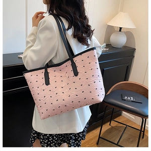 Détail du cabas rose plissé avec motifs nœuds noirs et bordure en cuir sur un mannequin