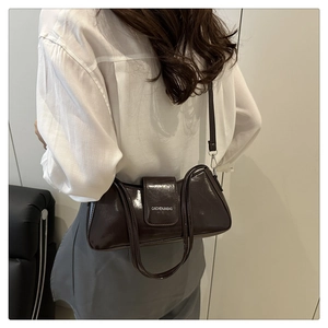 Detail of a dark brown glossy leather shoulder bag with logo on flap and sleek finish