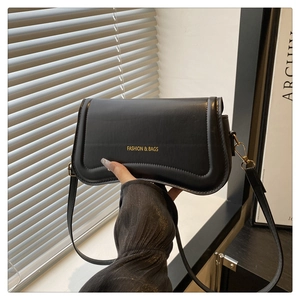 Detail of black leather crossbody bag with FASHION & BAGS gold lettering and U-shaped texture