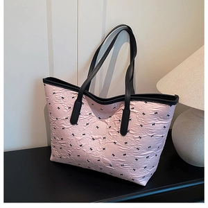 Détail du sac cabas rose avec motifs de nœuds noirs et texture de tissu gaufré