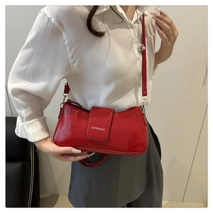 Detail of red patent leather crossbody bag with white logo and silver metal hooks