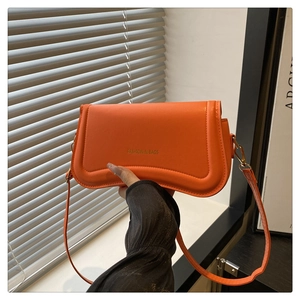 Close-up of vibrant orange crossbody bag with Fashion & Bags text on textured surface