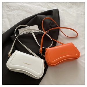 Detail of minimalist white and orange crossbody bags with fashion lettering on textured fabric