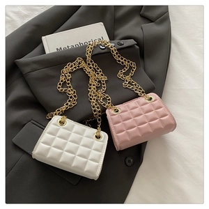 Detail of quilted texture and gold chain on white and pink crossbody bags over a blazer