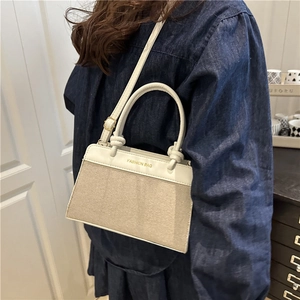 Chic beige canvas and white leather tote bag with gold lettering shown in cross-body view