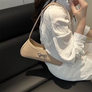 Elegant beige baguette bag with silver metal bow detail and slim shoulder strap