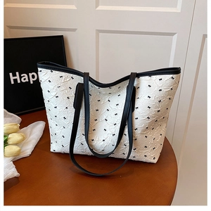 Détail du sac cabas blanc avec motifs de nœuds noirs sur tissu texturé pour l'été