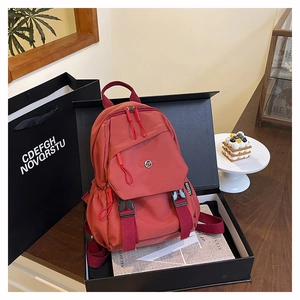Détail d'un grand sac à dos en nylon rouge brique dans un coffret cadeau de luxe