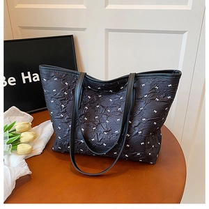 Détail du grand sac cabas noir avec motifs de nœuds blancs et anses en similicuir
