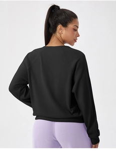 Détail du tissu gaufré noir et de la coupe à épaules tombantes sur ce haut de sport à manches