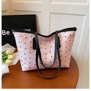 Sac fourre-tout plissé rose à pois nœuds noirs posé sur une table en bois rustique