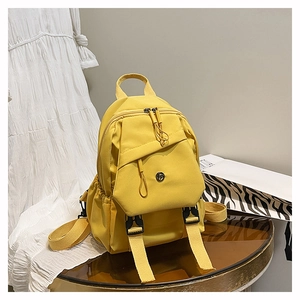 Détail d'un sac à dos en nylon jaune vif avec rabat à boucle et poches latérales pratiques