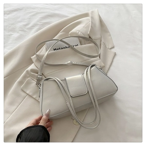 Silver-gray metallic faux leather shoulder bag with adjustable straps on a beige blazer