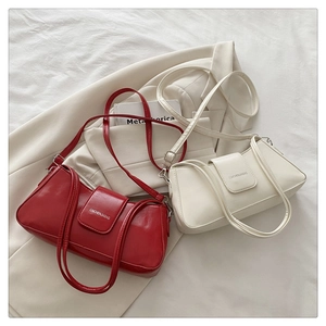 Detail of red and beige baguette underarm bags with glossy PU leather and silver hardware