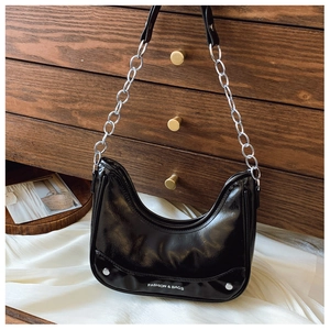 Detail of black patent leather hobo bag with silver rivets and metal chain strap