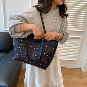 Sac fourre-tout noir matelassé avec motif nœuds blancs et lanières en cuir sur modèle