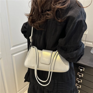 Minimalist light grey leather baguette shoulder bag shown on model with elegant styling