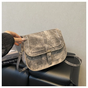 Detail of vintage grey washed denim saddle bag with metal buckle and shoulder strap