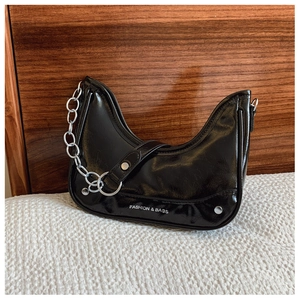Détail du sac en cuir verni noir avec chaîne argentée et clous métalliques de style