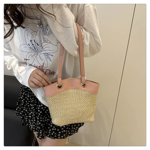 Detail of pink leather trim and beige woven straw texture on large bucket bag