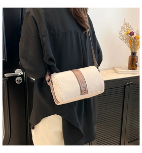 Detail view of the cylinder pillow bag with ethnic style strap shown on model shoulder
