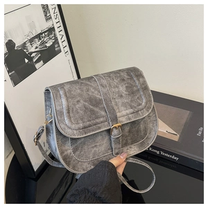 Detailed view of gray washed denim saddle bag with metal buckle on artistic background