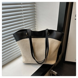 Detail of a chic woven tote bag with black leather straps and stylish metal ring buckle