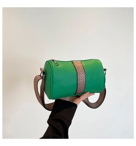 Detail of green leather cylinder bag with textured surface and vintage woven strap
