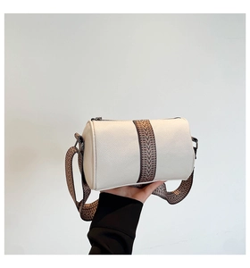 Detail of cream barrel bag showing lychee grain leather and geometric webbing strap