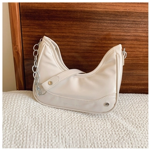 Détail du sac hobo crème avec chaîne argentée et gaufrage de lettres sur tissu texturé