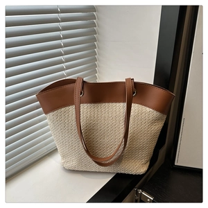 Close-up of woven straw texture and dark brown leather splicing on a chic summer tote bag