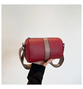 Detail of red pebbled leather Boston bag with geometric pattern woven shoulder strap