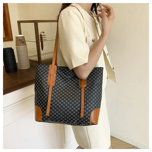 Détail d'un grand sac cabas à motifs porté par un mannequin dans un café moderne