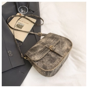 Detail view of vintage-style saddle bag with matte texture and metal buckle accents