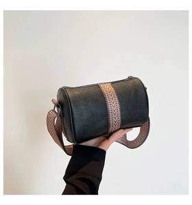Detail of black lychee grain leather cylinder bag with stylish wide vintage shoulder strap