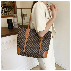 Détail d'un grand sac cabas imprimé vintage avec bordures en cuir marron et deux bandoulières